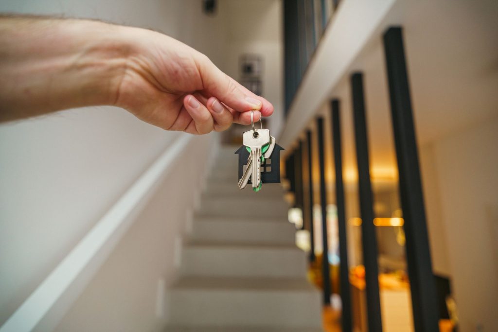 Mano sosteniendo las llaves de una vivienda en un interior luminoso